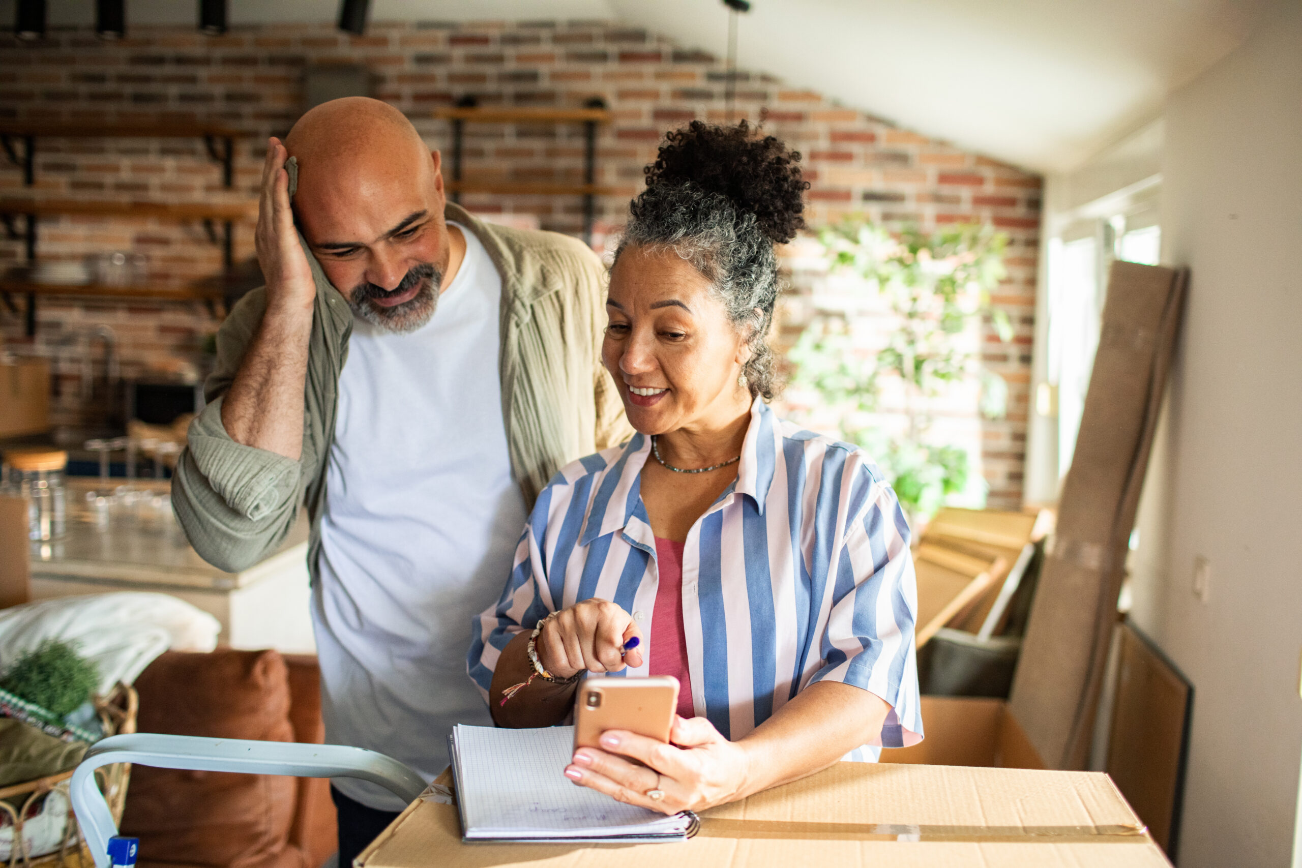 Couple using a phone to plan a home remodel budget and compare financing options for house upgrades.
